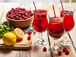 On wooden boards are ice cold beverage glasses with red raspberry lemon cocktail . Alcohol country cocktail beverage number hundred seventy two with mint. Group cocktail on wooden table.