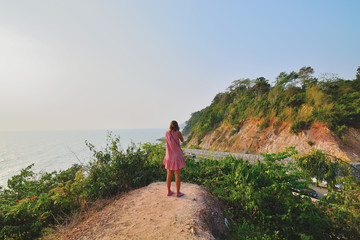 Woman standing shooting mountain road by the sea