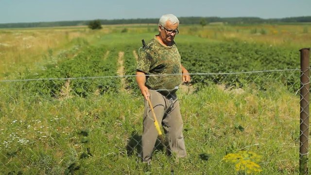 Man works with garden spray in the field near home