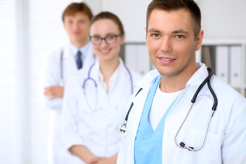 Fototapeta premium Cheerful smiling male doctor with medical staff at the hospital