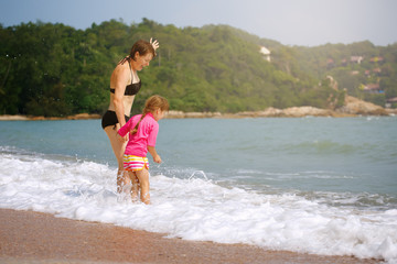 Happy family playing in blue water on a tropical resort at the s