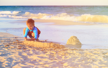 little boy play with sand on beach