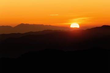 Brilliant and colorful orange sunset with silhouette of mountain range