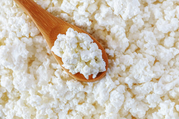 crumbly cottage cheese in the wooden spoon lying diagonally upwards - 115854447