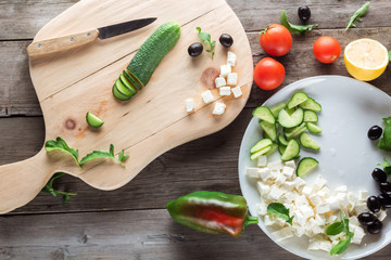 Fototapeta na wymiar Cooking Greek salad, cutting a cucumber