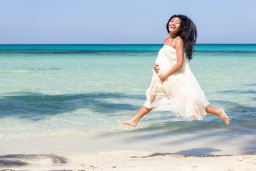 Fototapeta na wymiar pregnant woman jumping on the beach