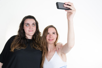 Two best female friends using smart phone and doing selfie.