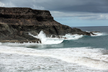 Wave splashing over a rock on the beach of Puertito de los Molinos on Fuerteventura. Canary Island, Spain
