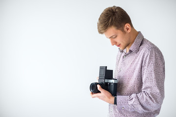 Portrait of handsome man with old medium format camera in studio