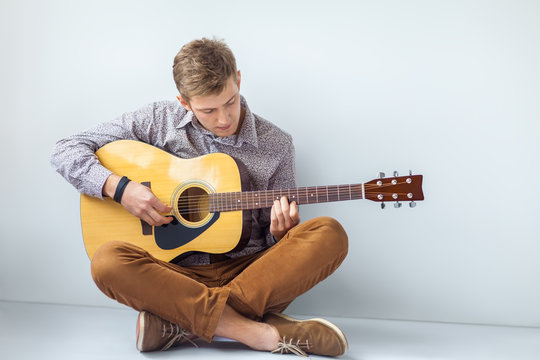 Portrait of handsome man playing guitar siting on floor