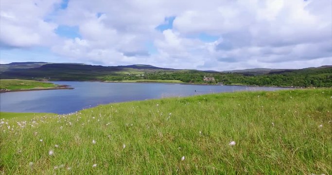 Views of Dunvegan Castle from Uiginish, green summer meadows and the blue water of Loch Dunvegan