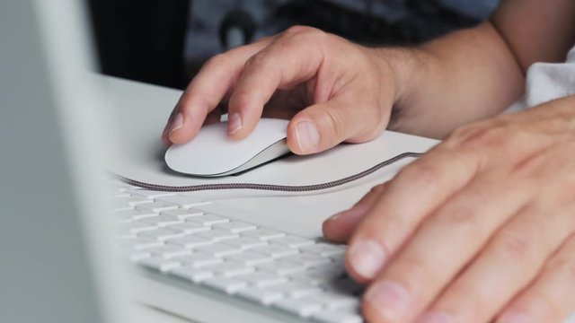 dolly shot of person working in modern office space. close-up on hands typing on keyboard
