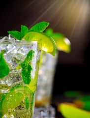 Mojito cocktail on a table. Summer cocktail with rum, lime, mint, ice cubes and brown sugar