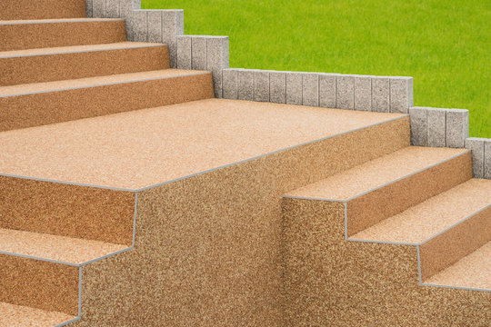 Komplizierte Betontreppe mit Kieselbeschichtung und Stelen aus Granit vor gepflegtem Rasen &ndash;-- Complicated concrete staircase with gravel coating and pillars of granite 