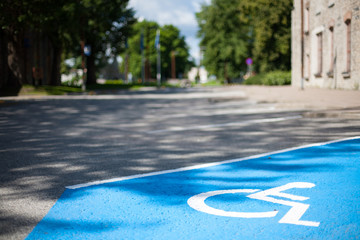 Closeup of an empty handicapped reserved parking space painted blue with a white wheelchair symbol...