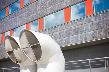 Industrial background of two big modern ventilation pipe tops in front of an office building