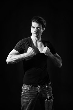 Black and white portrait of muscular man pulling his t-shirt