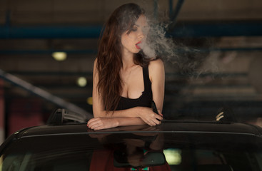 Young beautiful woman smoking ( vaping ) e-cigarette with smoke in car luke
