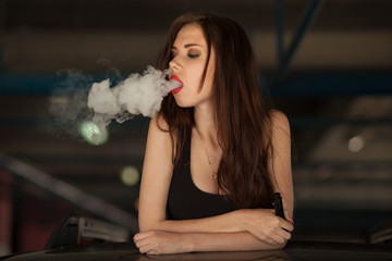 Young beautiful woman smoking ( vaping ) e-cigarette with smoke in car luke