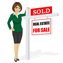 Female real estate agent standing next to a sold for sale sign