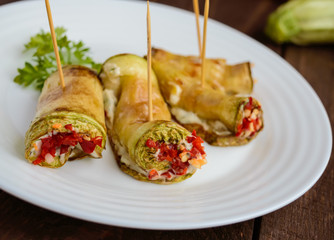 Sharp rolls zucchini, stuffed with garlic, herbs and chili peppers on a white plate. Close-up