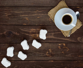 A cup of black coffee (espresso) and sweet marshmallow on a dark wooden background. top view