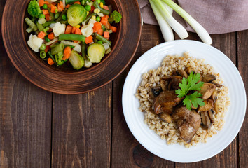 Barley porridge, fried mushrooms, duck liver and steamed summer vegetables - healthy food. The top view