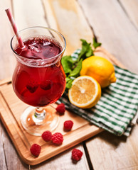 On wooden boards is ice cold beverage glass with red raspberry lemon cocktail . Alcohol country cocktail beverage number hundred seventy nine with checkered cloth. Top view cocktail .