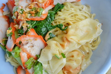 yellow noodle topping barbecue pork and dumpling on bowl
