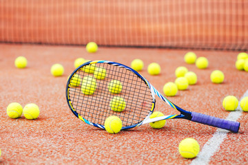 tennis racket with many balls on clay court..