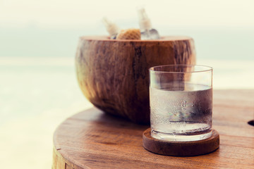 glass of water and moisturizers on table at beach