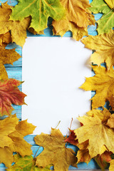 Naklejka na ściany i meble Autumn leaf with blank sheet on a blue wooden table