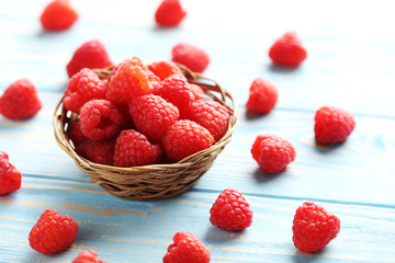 Red raspberries in basket on a blue wooden table