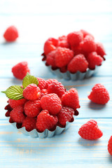 Red raspberries in bowl on a blue wooden table