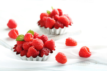Red raspberries in bowl on a white wooden table