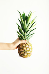 Female hand holding ripe pineapple on a white background