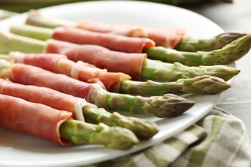 Fresh green asparagus wrapped in jamon on a grey table