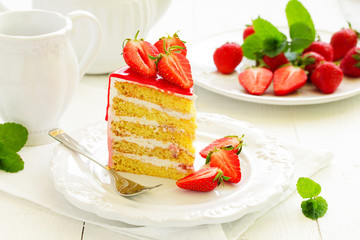 A piece of sponge cake with strawberries and cream.