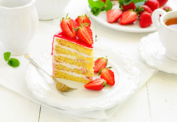 A piece of sponge cake with strawberries and cream.