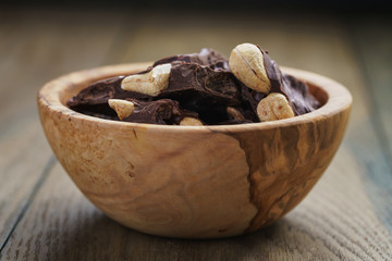 broken homemade bar of chocolate with cashew nuts in wood bowl