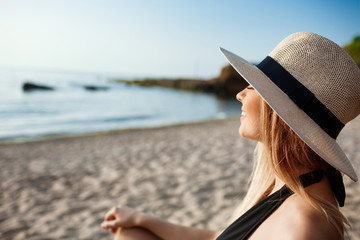 Fototapeta premium Beautiful young cheerful girl in hat rests at morning beach