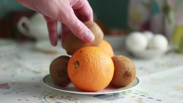Man takes an orange from a plate