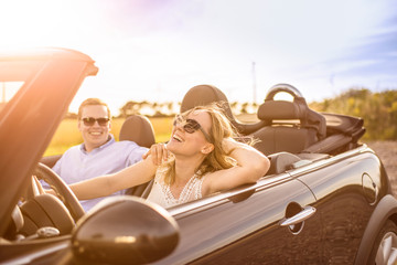 Mit dem Cabrio unterwegs - Verliebtes Paar im Cabrio lacht und ist glücklich  - obrazy, fototapety, plakaty