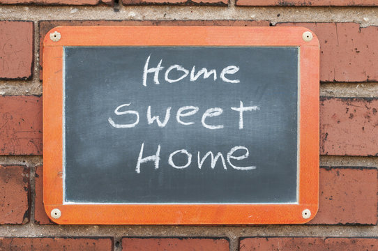 Tafel an einer Ziegelwand mit Text / Tafel an einer Ziegelwand mit Text Home sweet Home.