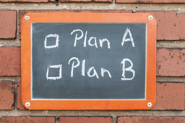 Tafel an einer Ziegelwand mit Text / Tafel an einer Ziegelwand mit Text Plan A, Plan B.