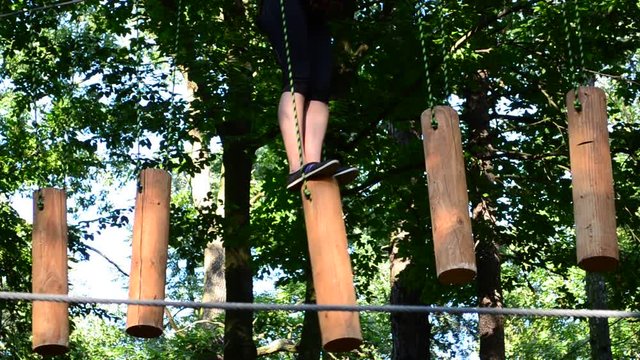 The girl the teenager overcomes obstacles between trees at height. Rope town.