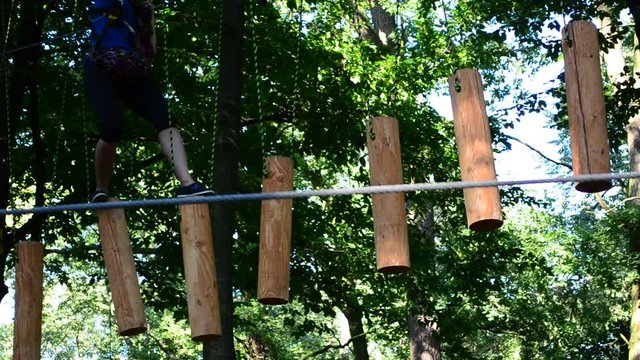 The girl the teenager overcomes obstacles between trees at height. Rope town.