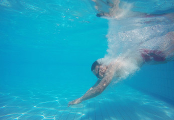 Obraz na płótnie Canvas Beard man with glasses diving in a pool