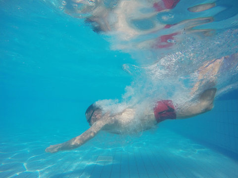 Beard man with glasses diving in a pool