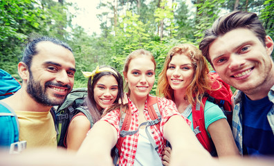 friends with backpack taking selfie in wood